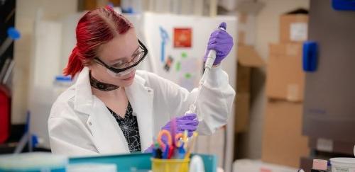 Female inserting a liquid into a container in science lab